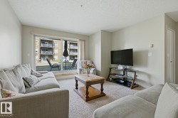 Living area featuring neutral wall tones, carpeted flooring, and a sliding glass door leading to an outdoor patio - 