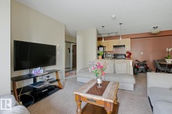 Open-concept living area with neutral carpeting, recessed lighting, and a kitchen featuring wood-finish cabinetry - 
