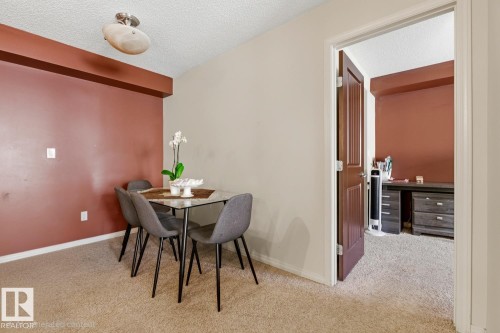 Neutral wall paint and an accent wall create a distinct dining area - #106 13907 136 St Nw, Edmonton, AB - Indoor Photo Showing Dining Room