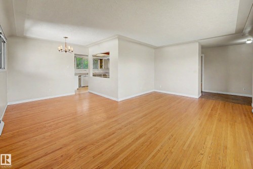 Hardwood flooring throughout, recessed opening to kitchen, and a chandelier lighting fixture - 9723 76 Street Nw, Edmonton, AB - Indoor Photo Showing Other Room