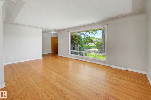 Hardwood flooring, light gray wall finishes, a large picture window, and a wood-finish interior door - 9723 76 Street Nw, Edmonton, AB - Indoor