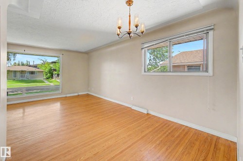 Hardwood flooring, two windows, and a ceiling-mounted chandelier - 9723 76 Street Nw, Edmonton, AB - Indoor Photo Showing Other Room