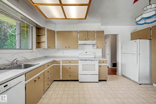 Full range of appliances, extensive cabinetry, double basin stainless steel sink, large window, and patterned flooring - 9723 76 Street Nw, Edmonton, AB - Indoor Photo Showing Kitchen