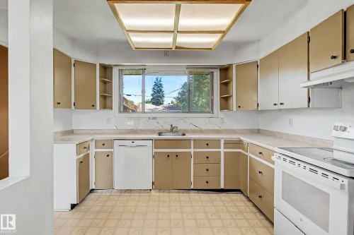 U-shaped kitchen layout with an integrated dishwasher, built-in electric range, and a window above the sink - 9723 76 Street Nw, Edmonton, AB - Indoor Photo Showing Kitchen