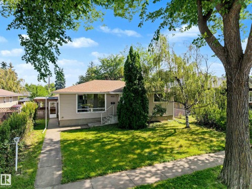 Single-story residence featuring light-toned siding, a low-pitch roof, and a prominent front picture window - 9723 76 Street Nw, Edmonton, AB - Outdoor