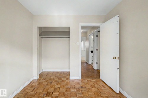 Parquet wood flooring with a built-in closet featuring a hanging rod - 9723 76 Street Nw, Edmonton, AB - Indoor Photo Showing Other Room