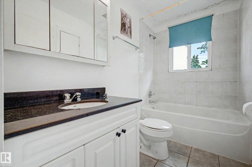 White vanity with dark countertop, undermount sink, and chrome fixtures - 9723 76 Street Nw, Edmonton, AB - Indoor Photo Showing Bathroom