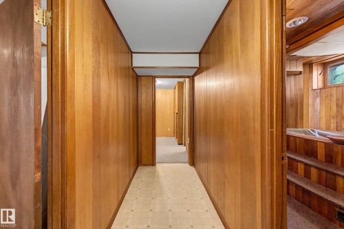 Hallway featuring wood paneling, patterned flooring, and an adjacent room with a built-in tub and wood paneling - 9723 76 Street Nw, Edmonton, AB - Indoor Photo Showing Other Room