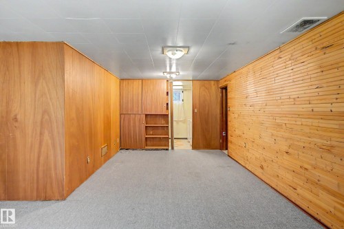 Wood paneling, drop ceiling, wall-mounted light fixtures, built-in cabinetry, and gray carpet - 9723 76 Street Nw, Edmonton, AB - Indoor Photo Showing Other Room
