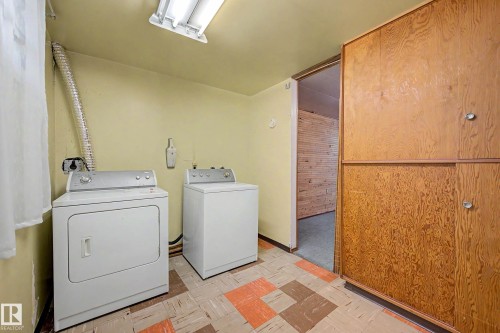 Utility area featuring a washer and dryer, built-in wood-finish cabinetry, and patterned floor tiles - 9723 76 Street Nw, Edmonton, AB - Indoor Photo Showing Laundry Room