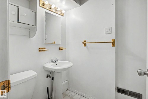 Pedestal sink with chrome-finish faucet, wall-mounted mirror, and overhead vanity lighting - 9723 76 Street Nw, Edmonton, AB - Indoor Photo Showing Bathroom