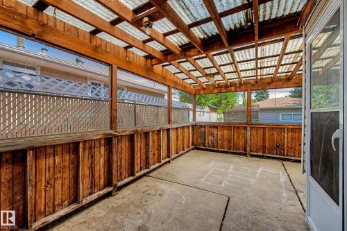 Covered patio featuring a corrugated translucent roof, exposed wooden beams, and a concrete floor - 9723 76 Street Nw, Edmonton, AB - Outdoor With Exterior
