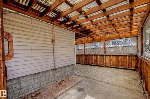 Covered patio featuring a concrete floor, wood beam ceiling, and wood-paneled walls - 9723 76 Street Nw, Edmonton, AB -  With Exterior