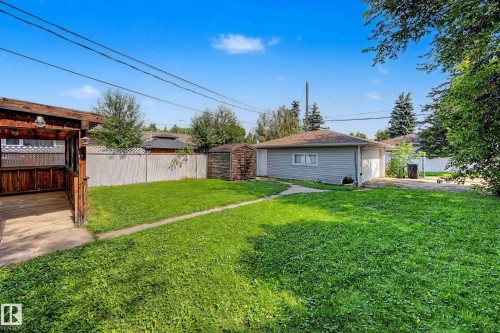 Expansive lawn with a detached garage featuring siding and a shingled roof, a wooden gazebo with a latticed railing, and a privacy fence - 9723 76 Street Nw, Edmonton, AB - Outdoor