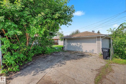 Detached two-car garage with light-colored siding, a shingled roof, and a concrete driveway - 9723 76 Street Nw, Edmonton, AB - Outdoor