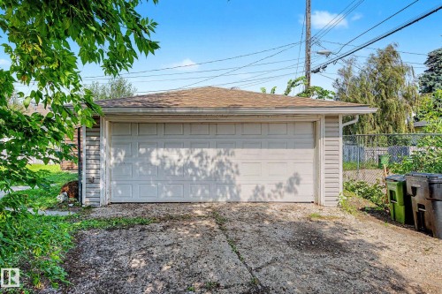 Detached garage featuring a paneled overhead door, shingle roof, and light-colored siding - 9723 76 Street Nw, Edmonton, AB - Outdoor