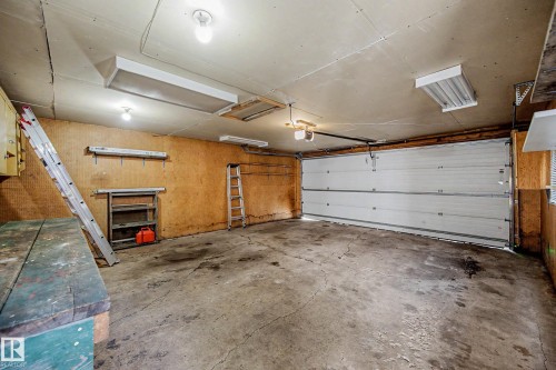 Attached garage featuring a sectional door and exposed wall paneling - 9723 76 Street Nw, Edmonton, AB - Indoor Photo Showing Garage