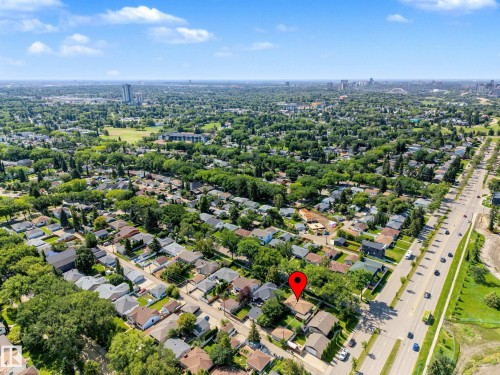 Aerial perspective showcasing a residential neighborhood with ample tree cover, proximity to a multi-lane roadway, and distant city skyline - 9723 76 Street Nw, Edmonton, AB - Outdoor With View