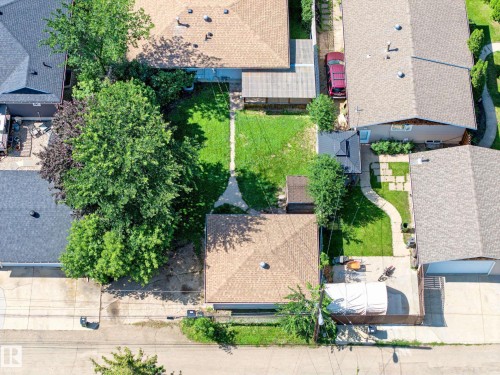 Expansive backyard featuring a manicured lawn, established trees, and concrete pathways - 9723 76 Street Nw, Edmonton, AB - Outdoor
