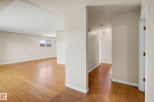 Hardwood-style flooring extends through the main area, complemented by crisp white trim and neutral wall tones - 9723 76 Street Nw, Edmonton, AB - Indoor Photo Showing Other Room