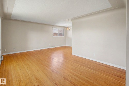 Hardwood flooring throughout, neutral wall finishes, and a chandelier lighting fixture - 9723 76 Street Nw, Edmonton, AB - Indoor Photo Showing Other Room