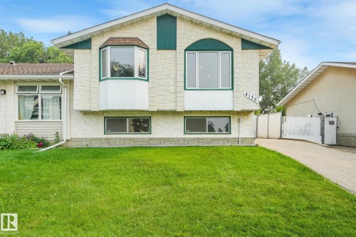 Split-level home featuring a light-colored textured exterior, a green gabled roofline, and a prominent bay window - 4135 134 Avenue Nw, Edmonton, AB - Outdoor