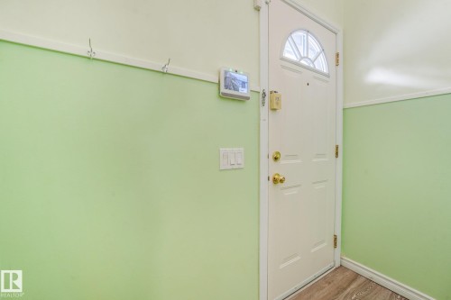 Entryway featuring a white paneled door with an arched window, brass hardware, and wood-finish flooring - 4135 134 Avenue Nw, Edmonton, AB - Indoor Photo Showing Other Room