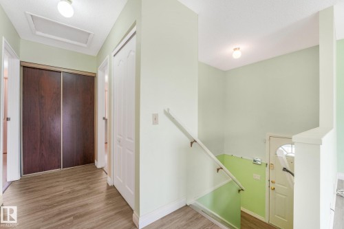 Hallway featuring wood-finish flooring, a wood-panel sliding door closet, and white trim - 4135 134 Avenue Nw, Edmonton, AB - Indoor Photo Showing Other Room