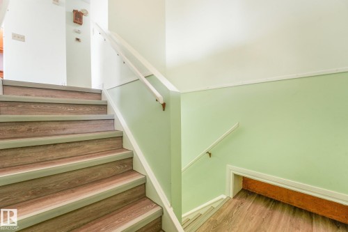 Stairwell featuring wood-finish treads with light gray risers and nosing, white handrails, and a light green lower wall panel - 4135 134 Avenue Nw, Edmonton, AB - Indoor Photo Showing Other Room