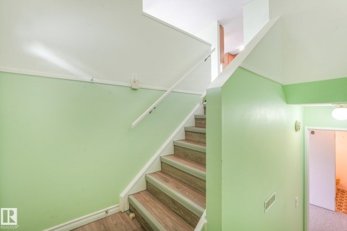 Staircase featuring wood-finish treads, white risers, and a white handrail - 4135 134 Avenue Nw, Edmonton, AB - Indoor Photo Showing Other Room