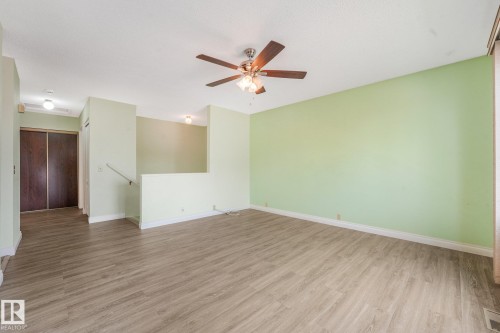Spacious living area featuring wood-finish flooring, a ceiling fan, and light green walls - 4135 134 Avenue Nw, Edmonton, AB - Indoor Photo Showing Other Room