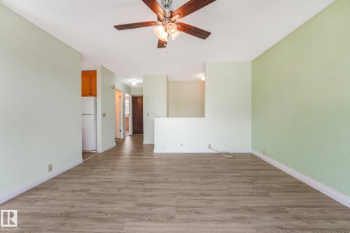 Spacious room featuring wood-finish flooring, light green walls, white baseboards, and a ceiling fan with integrated lighting - 4135 134 Avenue Nw, Edmonton, AB - Indoor Photo Showing Other Room