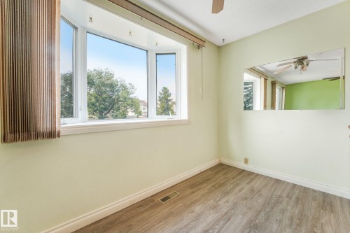 Bay window offering neighborhood views, wood-finish flooring, ceiling fan, and light green wall finish - 4135 134 Avenue Nw, Edmonton, AB - Indoor Photo Showing Other Room