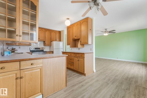 Kitchen featuring light wood cabinetry, a white tile backsplash, and a white refrigerator - 4135 134 Avenue Nw, Edmonton, AB - Indoor Photo Showing Kitchen