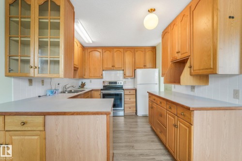 Kitchen featuring extensive wood cabinetry, white countertops, stainless steel range, and a white tile backsplash - 4135 134 Avenue Nw, Edmonton, AB - Indoor Photo Showing Kitchen With Double Sink