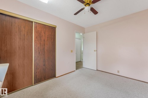 Room featuring wood-finish sliding closet doors, ceiling fan with light fixture, light-colored carpeting, and neutral wall paint - 4135 134 Avenue Nw, Edmonton, AB - Indoor Photo Showing Other Room