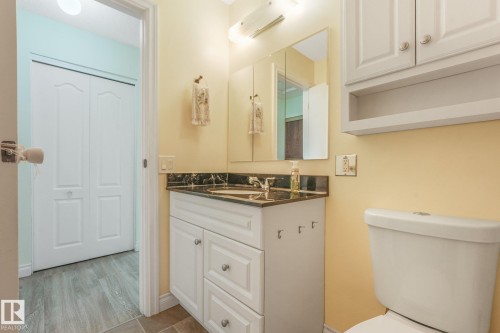 Bathroom featuring a white vanity with paneling and drawer storage, topped with a dark countertop and integrated sink - 4135 134 Avenue Nw, Edmonton, AB - Indoor Photo Showing Bathroom