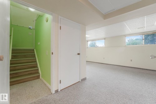 Spacious lower-level room featuring light gray carpet flooring and two windows, providing natural illumination - 4135 134 Avenue Nw, Edmonton, AB - Indoor