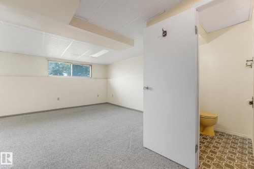 Spacious interior featuring light gray carpeting, a drop ceiling, and a single window - 4135 134 Avenue Nw, Edmonton, AB - Indoor