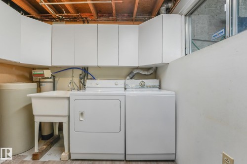 Laundry area featuring white cabinetry, a utility sink, and wood-finish flooring - 4135 134 Avenue Nw, Edmonton, AB - Indoor Photo Showing Laundry Room