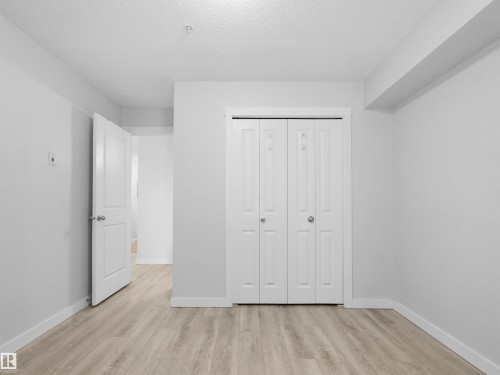 Light-toned wood-finish flooring complements white walls, baseboards, and trim - #205 5816 Mullen Pl Nw, Edmonton, AB - Indoor