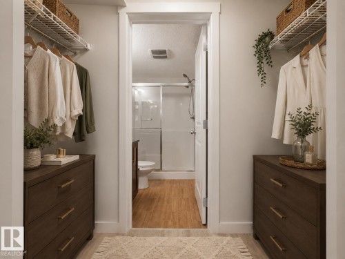 Walk-in closet featuring built-in wire shelving, integrated wood-finish drawer units with gold-tone hardware, and light-toned flooring - #205 5816 Mullen Pl Nw, Edmonton, AB - Indoor Photo Showing Bathroom