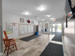 Tiled flooring leading to an exterior glass door, with built-in mailboxes and overhead lighting - 