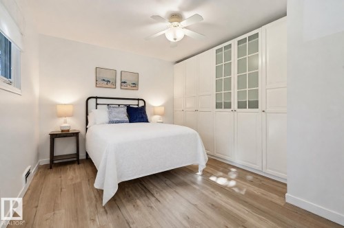 Wood-finish flooring, white built-in cabinetry with frosted glass panels, and a ceiling fan with integrated lighting - 9127 149 Street Nw, Edmonton, AB - Indoor Photo Showing Bedroom