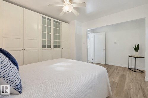 Built-in white cabinetry with frosted glass panels, wood-finish flooring, and a ceiling fan with integrated lighting - 9127 149 Street Nw, Edmonton, AB - Indoor Photo Showing Bedroom