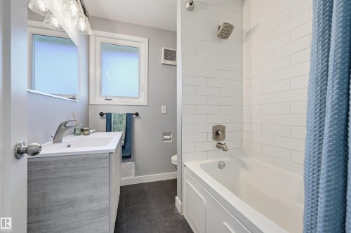 Bathroom with wood-finish vanity, white integrated sink, chrome faucet, and subway tile shower surround - 9127 149 Street Nw, Edmonton, AB - Indoor Photo Showing Bathroom