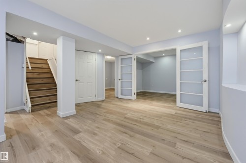 Recessed lighting, wood-finish flooring, white paneled doors, and double French doors with frosted glass panels - 9127 149 Street Nw, Edmonton, AB - Indoor Photo Showing Other Room