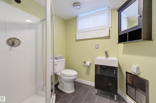 Glass-enclosed shower with a rain showerhead, contemporary vanity with an integrated sink, wall-mounted medicine cabinet, and large-format floor tiles - 9127 149 Street Nw, Edmonton, AB - Indoor Photo Showing Bathroom
