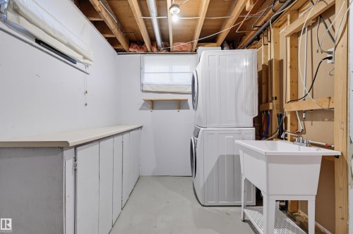 Laundry area featuring built-in cabinetry, an integrated countertop, a utility sink, and exposed ceiling joists - 9127 149 Street Nw, Edmonton, AB - Indoor
