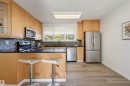 Kitchen featuring wood-finish cabinetry, stainless steel appliances, black countertops, and a tile backsplash - 9127 149 Street Nw, Edmonton, AB  - Indoor Photo Showing Kitchen 